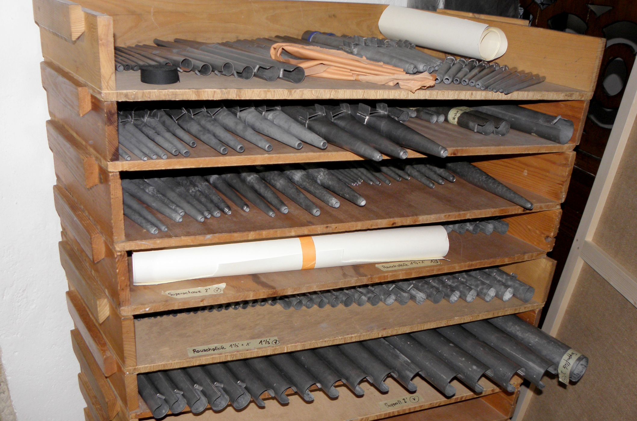 Holzregal voller Orgelpfeifen aus Metall.