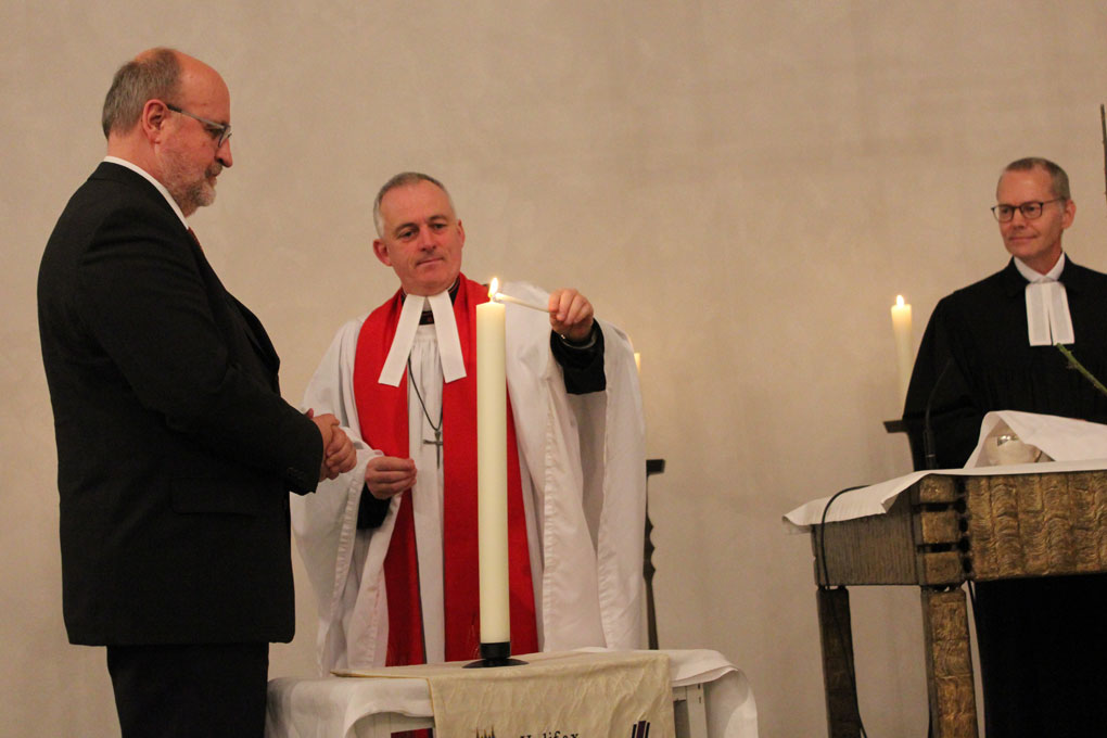 Superintendent Hans-Peter Bruckhoff und Reverend Canon Hilary Barber entzünden gemeinsam die Partnerschaftskerze, die das Halifax Minster dem Kirchenkreis Aachen schenkte.